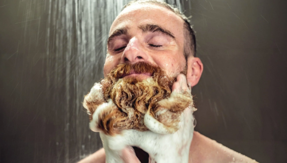 Zamyślony mężczyzna pod prysznicem myjący brodę szamponem do brody