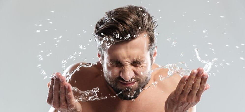 Mężczyzna myjący twarz wodą