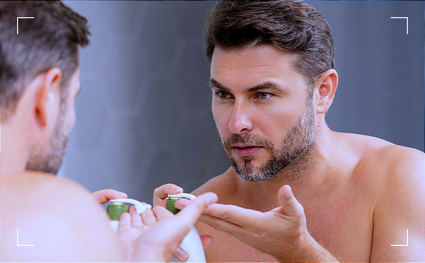 Mężczyzna patrzący w lustro, nakładający na rękę krem
